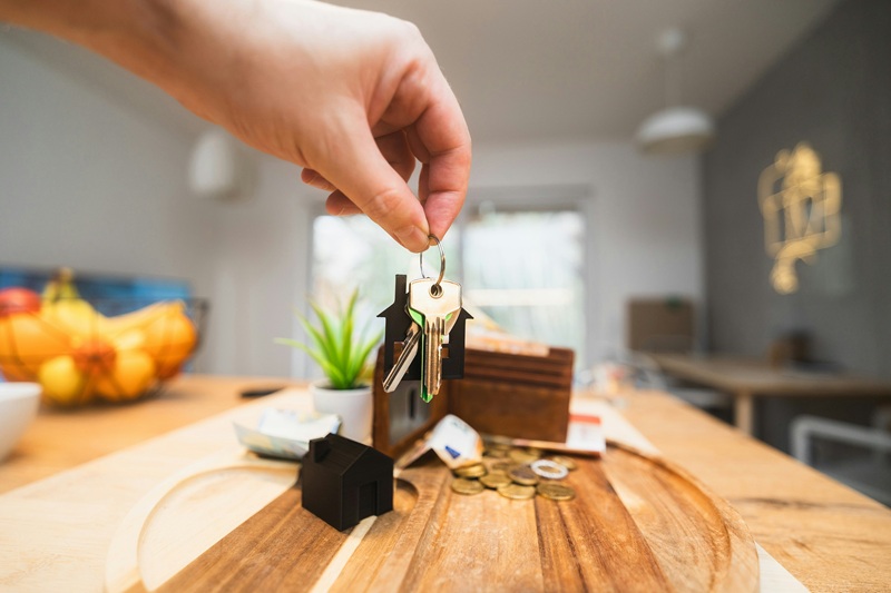 Photo of person holding house keys above wooden table | James Hardie siding contractor | Kenny Construction Group